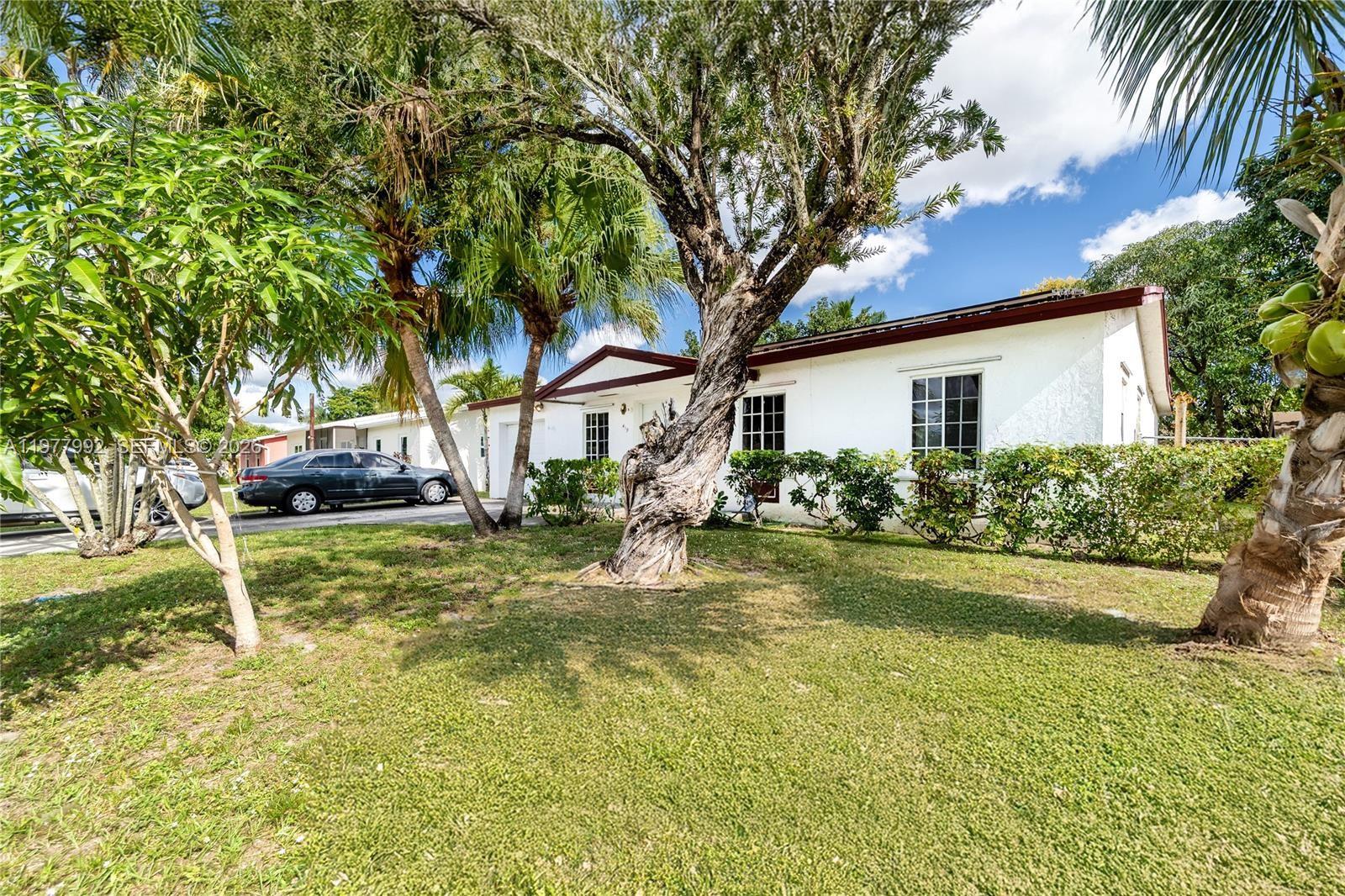 A white single-story house with a brown roof sits behind a lawn and mature trees — 419 SW 80th Ave, Pompano Beach FL 33068, POMPANO BEACH, FL