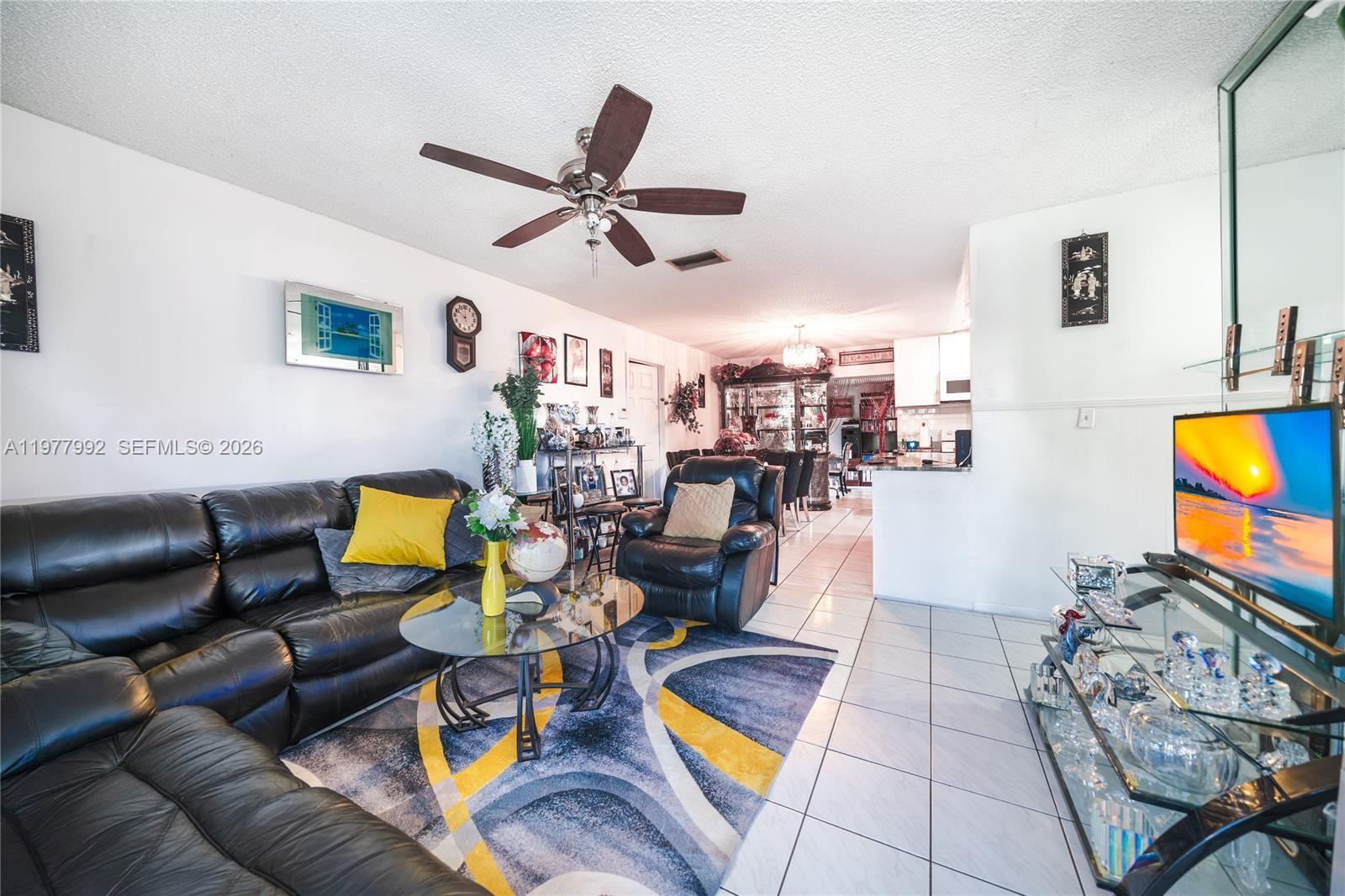 A living room features a black leather sofa, a glass coffee table, and tile flooring — 419 SW 80th Ave, Pompano Beach FL 33068, POMPANO BEACH, FL