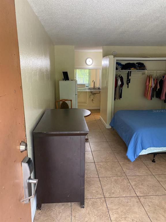 A studio apartment features a bed, open closet, dresser, and a small kitchen area — 7900 S ORANGE BLOSSOM TRAIL UNIT 2123, ORLANDO, FL
