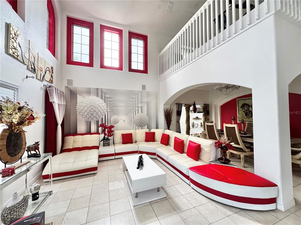 A living room features a large white and red sectional sofa, tile floors, and high ceilings — 2561 THE OAKS BOULEVARD, KISSIMMEE, FL