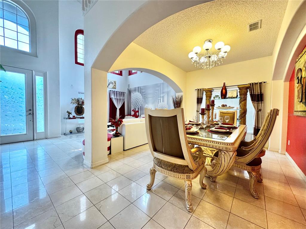 A dining room with an ornate table and chairs sits beneath an arched entryway — 2561 THE OAKS BOULEVARD, KISSIMMEE, FL