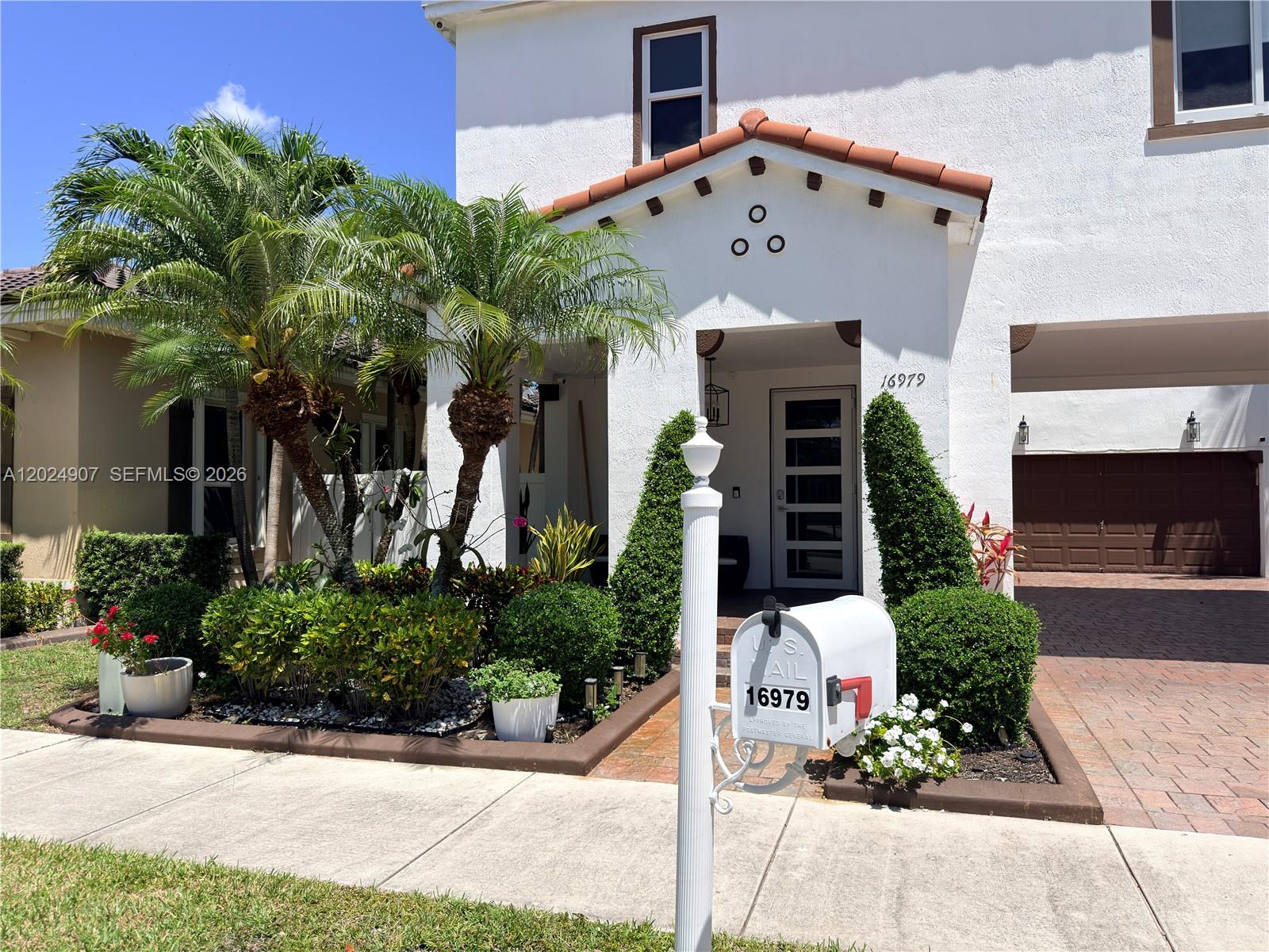 A white two-story house features a tiled roof, palm trees, and a front mailbox — MIAMI, FL