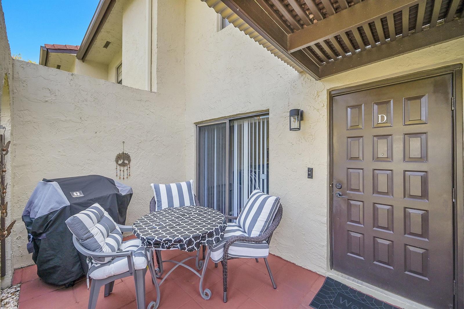 A beige two-story townhouse exterior features arched entryways, a front door labeled D, and landscaping — 21207 Lago Circle, Boca Raton FL 33433, BOCA RATON, FL