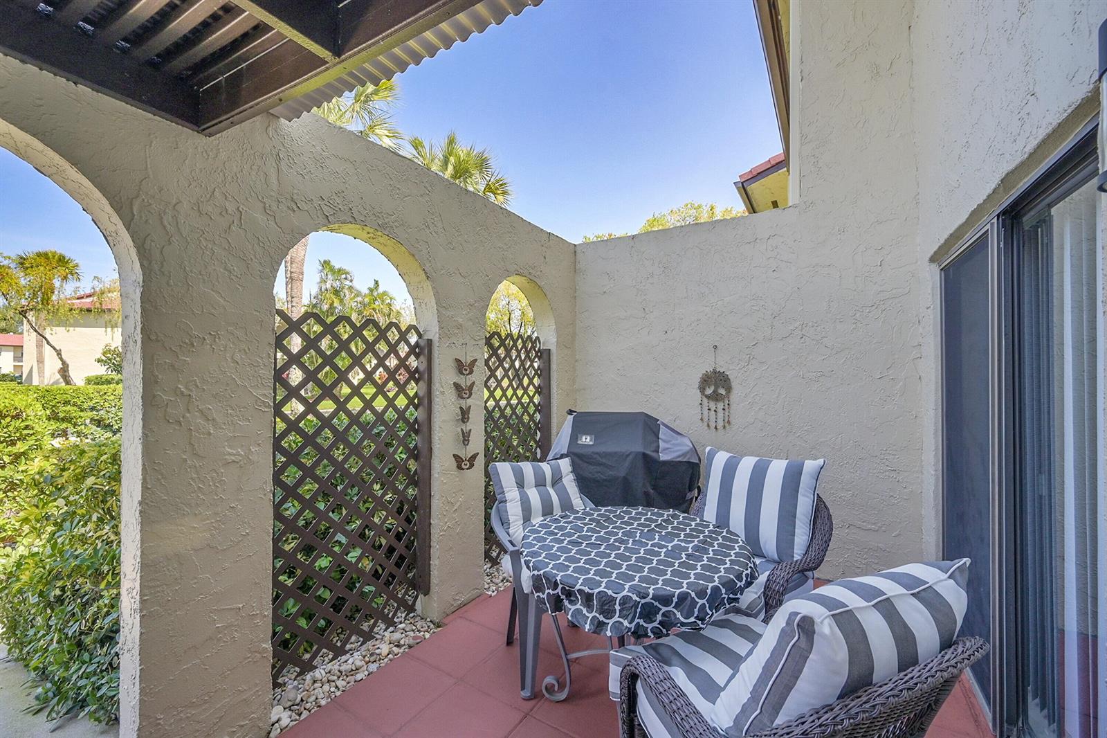 A patio features a small table with two chairs, a covered grill, and a brown door — 21207 Lago Circle, Boca Raton FL 33433, BOCA RATON, FL