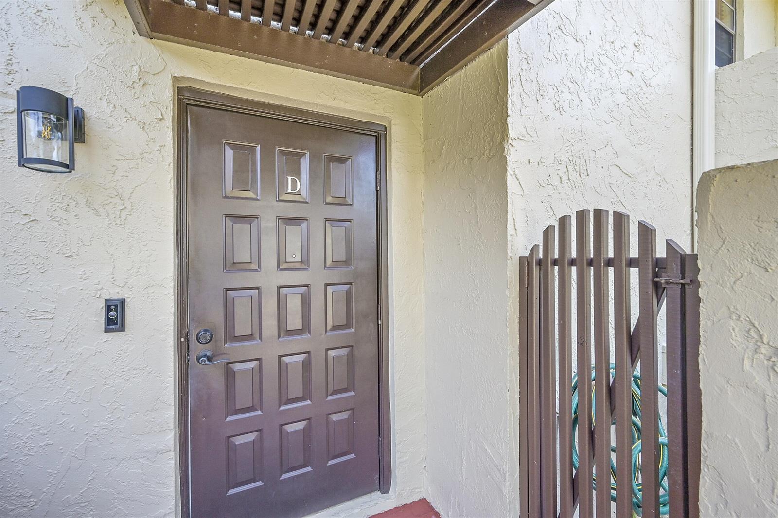 A covered patio features arched openings, lattice privacy screens, a small dining set, and a grill — 21207 Lago Circle, Boca Raton FL 33433, BOCA RATON, FL