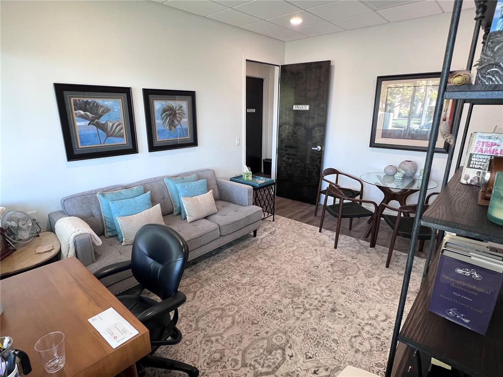 A furnished office features a gray sofa, a small round table, and a desk — 515 W BAY STREET UNIT 100, 101, TAMPA, FL