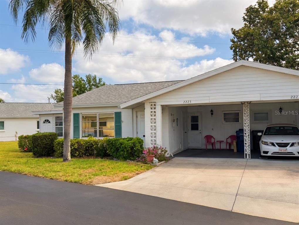 A white single-story house with a palm tree, carport, and a paved driveway — 2225 ORANGE BLOSSOM LANE, BRADENTON, FL