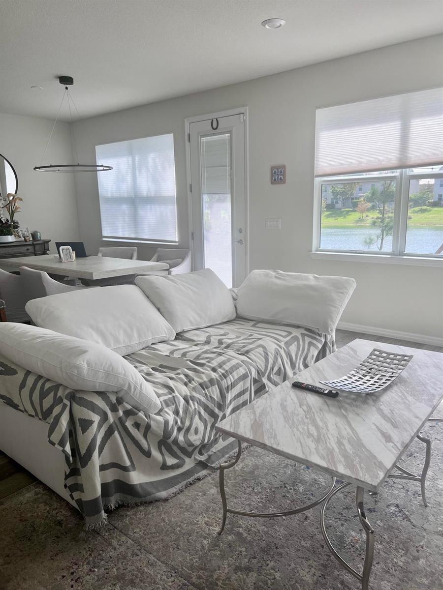 A living room features a white sofa with a patterned throw, marble table, and lake view — 4924 Greenway Drive, Hollywood FL 33021, HOLLYWOOD, FL