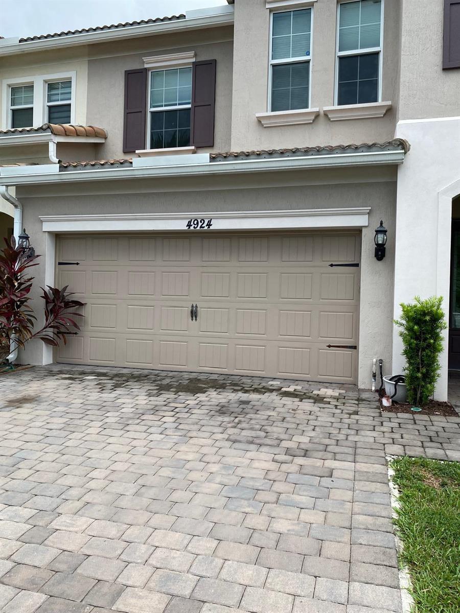 A beige two-story house features a double garage with decorative hardware and a paver driveway — 4924 Greenway Drive, Hollywood FL 33021, HOLLYWOOD, FL