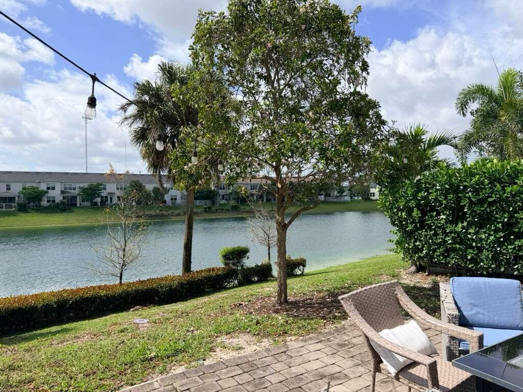 A patio with wicker furniture overlooks a lake, a grassy lawn, and residential buildings — 4924 Greenway Drive, Hollywood FL 33021, HOLLYWOOD, FL