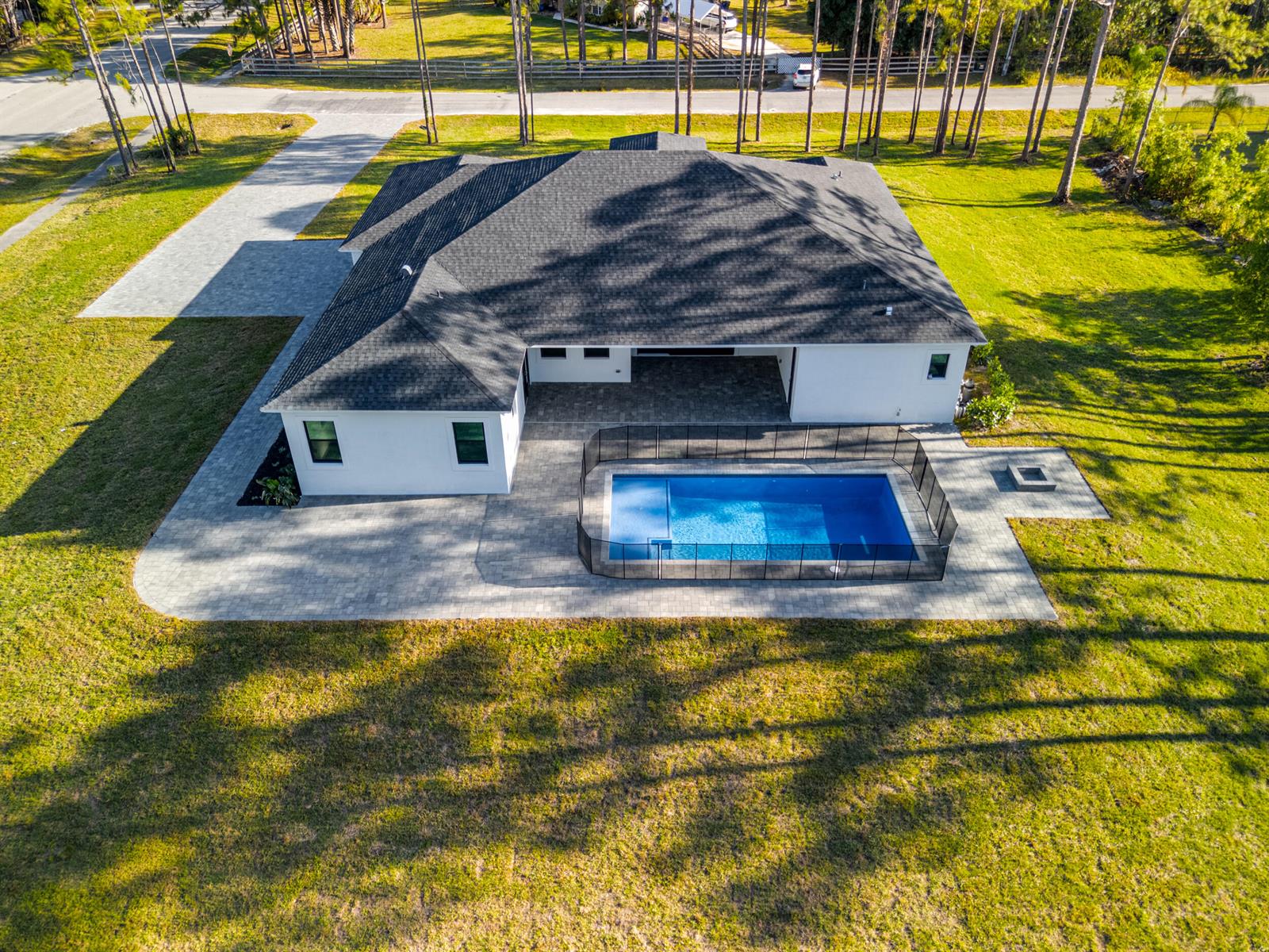 An aerial view of a white house with a dark roof, pool, and paved patio — 17975 81st Lane N, Loxahatchee FL 33470, LOXAHATCHEE, FL