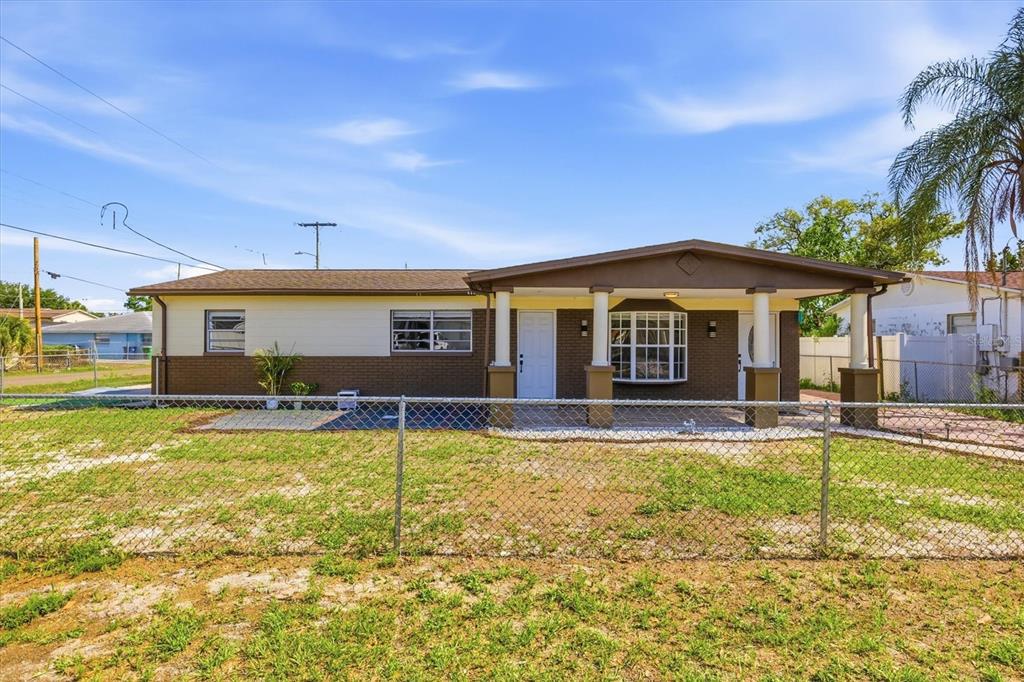 A single-story house with a brown brick facade, a covered porch, and a chain-link fence — 3002 W HAYA STREET, TAMPA, FL