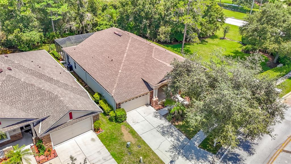 An aerial view shows two suburban houses with shingled roofs, driveways, and surrounding green landscaping — 7220 NIGHT HERON DRIVE, LAND O LAKES, FL