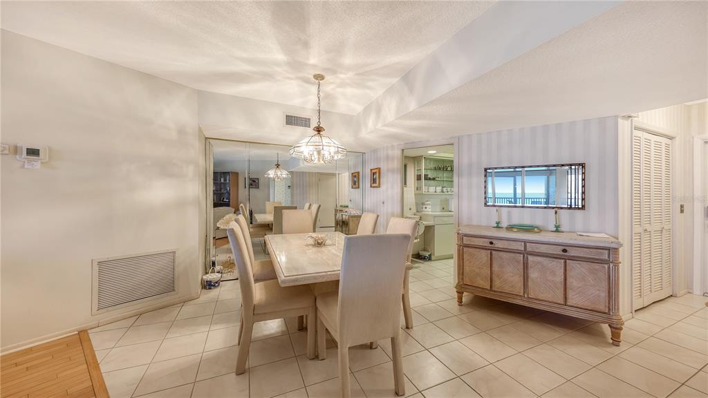 A dining room with a marble table, upholstered chairs, tiled floors, and a wooden sideboard — 4825 GULF OF MEXICO DRIVE UNIT 504, LONGBOAT KEY, FL