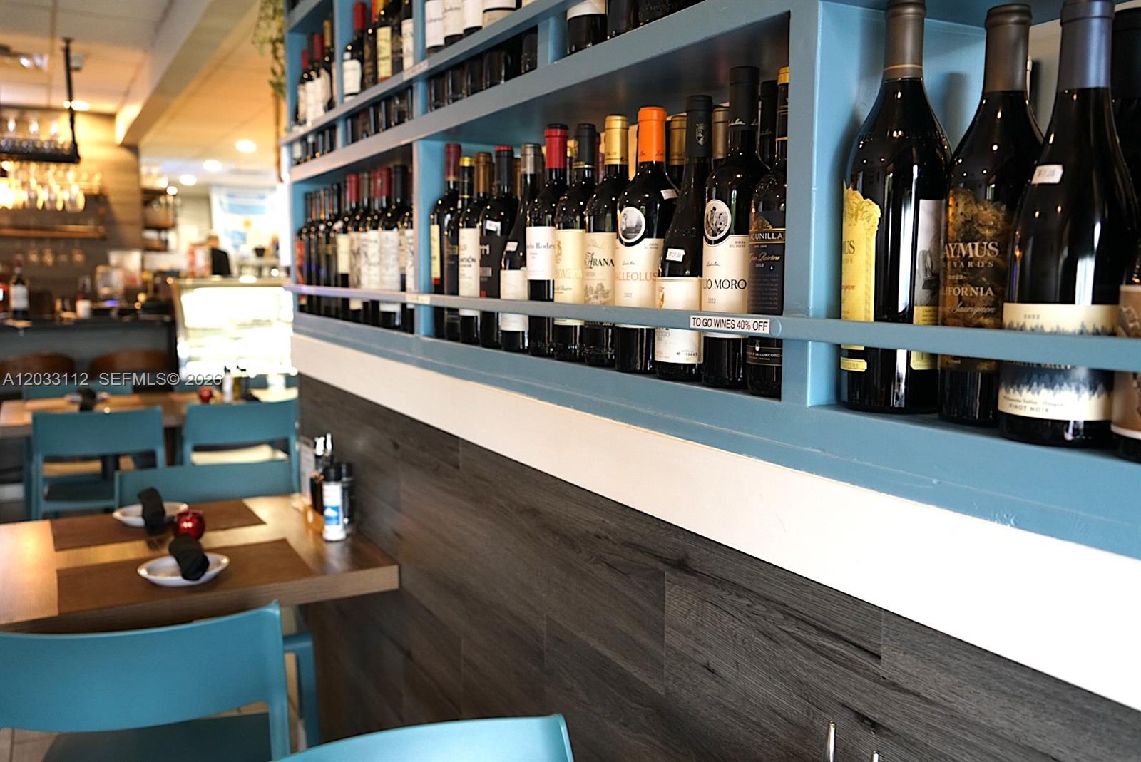 A restaurant interior features a blue shelving unit displaying wine bottles above dark wood paneling — 2752-2756 SW 137TH  AVE, Kendall FL 33175, KENDALL, FL