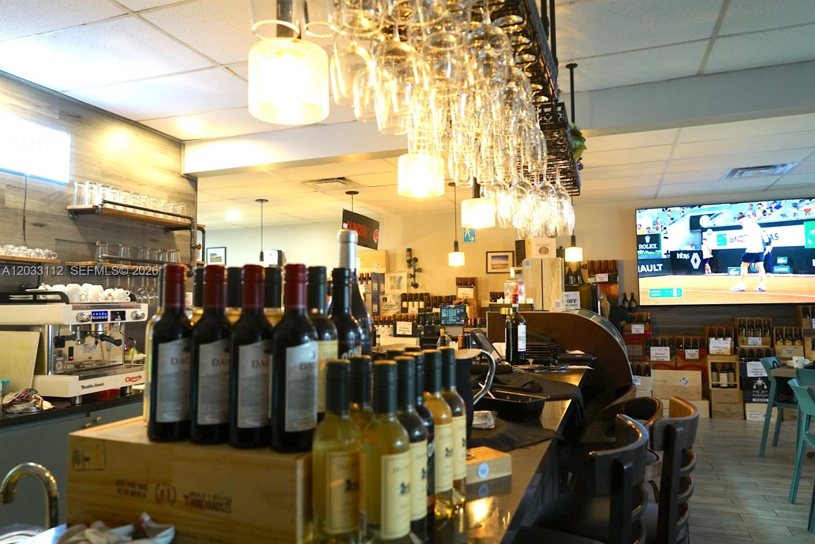 A restaurant bar features wine bottles on the counter, hanging glassware, and a large television — 2752-2756 SW 137TH  AVE, Kendall FL 33175, KENDALL, FL