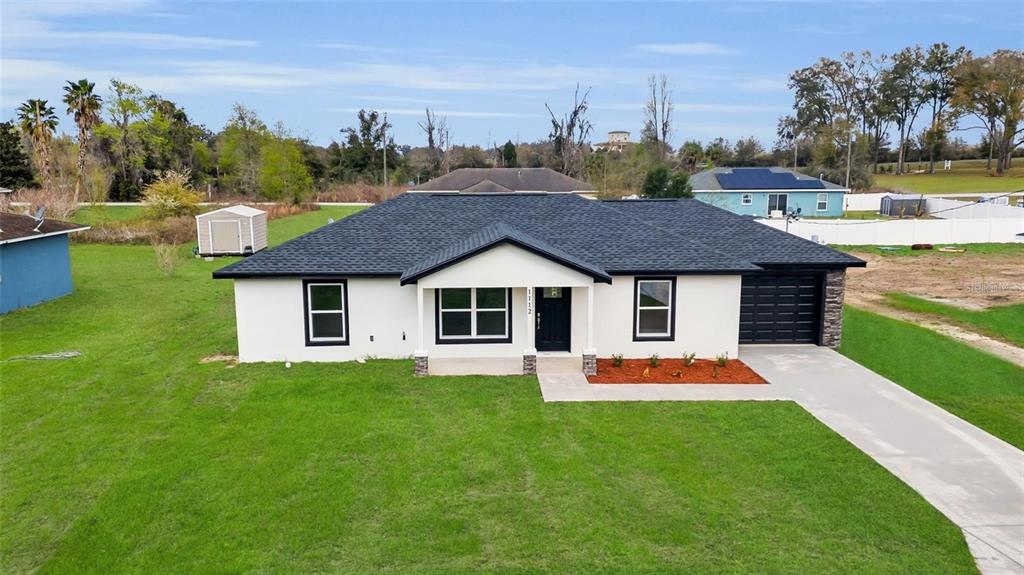 A single-story house with white stucco walls, a dark roof, and a front-facing garage — 14619 SW 21 PLACE, OCALA, FL