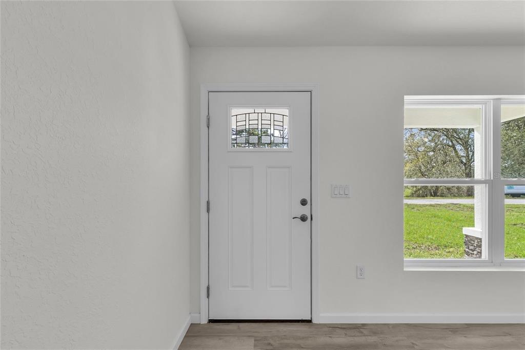 An interior view of an entryway featuring a white door with a window and light flooring — 14619 SW 21 PLACE, OCALA, FL