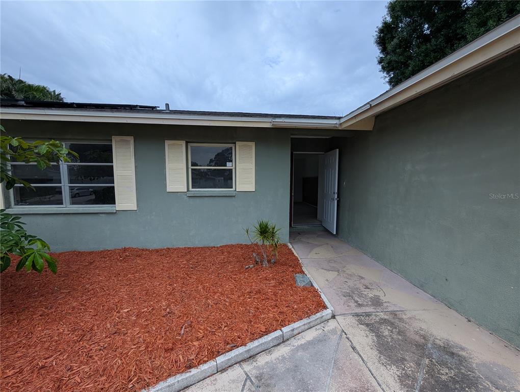 The exterior of a single-story house features green stucco walls, white shutters, and a walkway — 3646 LAKEWOOD DRIVE, SARASOTA, FL