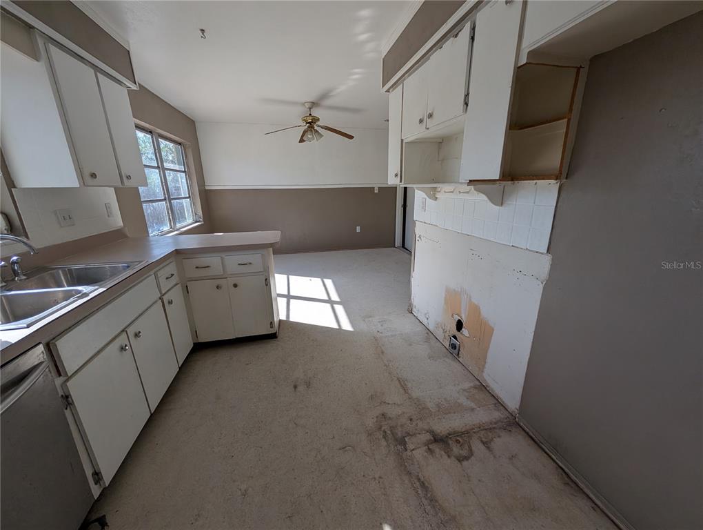 A kitchen with white cabinets, a stainless steel sink, and unfinished flooring and walls — 3646 LAKEWOOD DRIVE, SARASOTA, FL
