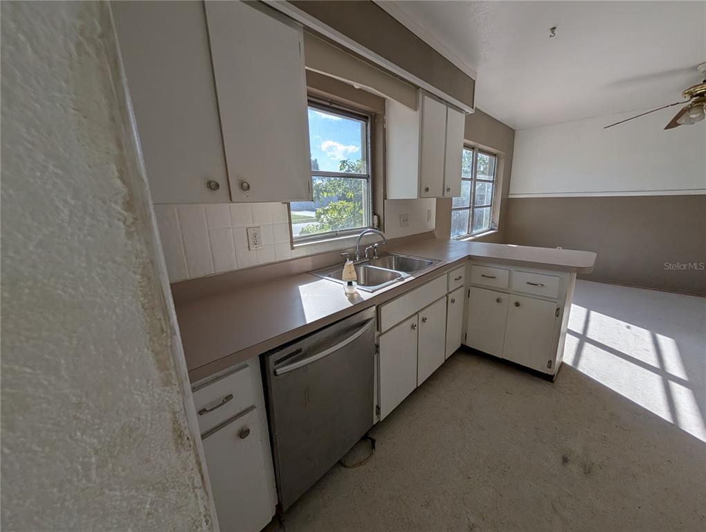 A kitchen features white cabinets, a stainless steel dishwasher, a double sink, and beige countertops — 3646 LAKEWOOD DRIVE, SARASOTA, FL