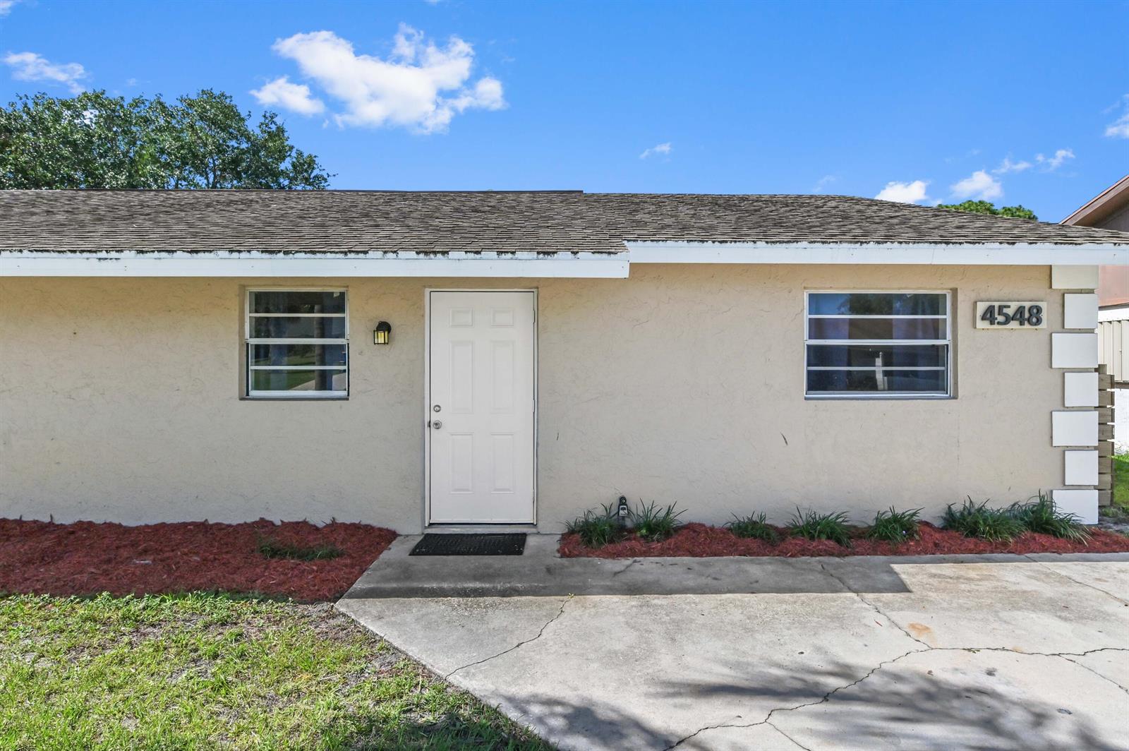 A single-story house exterior features a white door, two windows, and a concrete driveway — 4548 SE Salvatori Road, Stuart FL 34997, STUART, FL