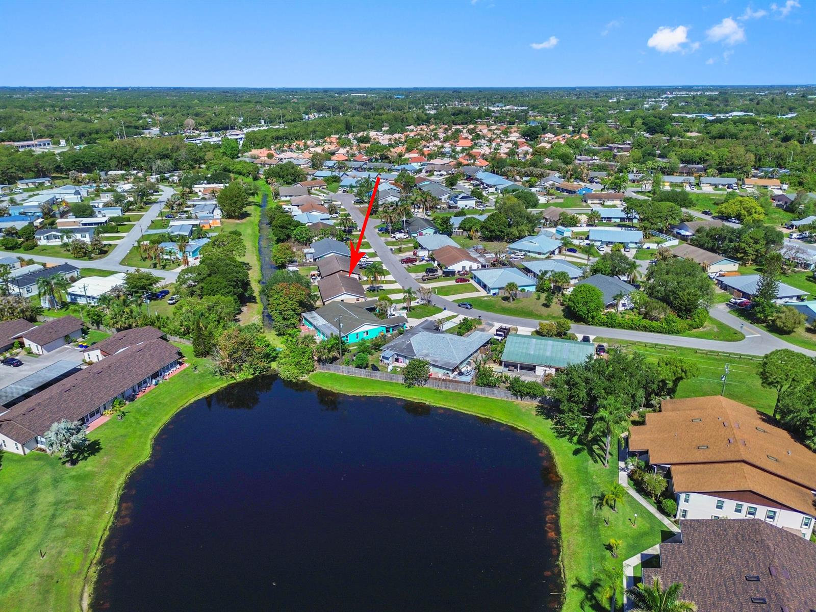 An aerial view shows a residential neighborhood with a lake and a red arrow pointing down — 4548 SE Salvatori Road, Stuart FL 34997, STUART, FL