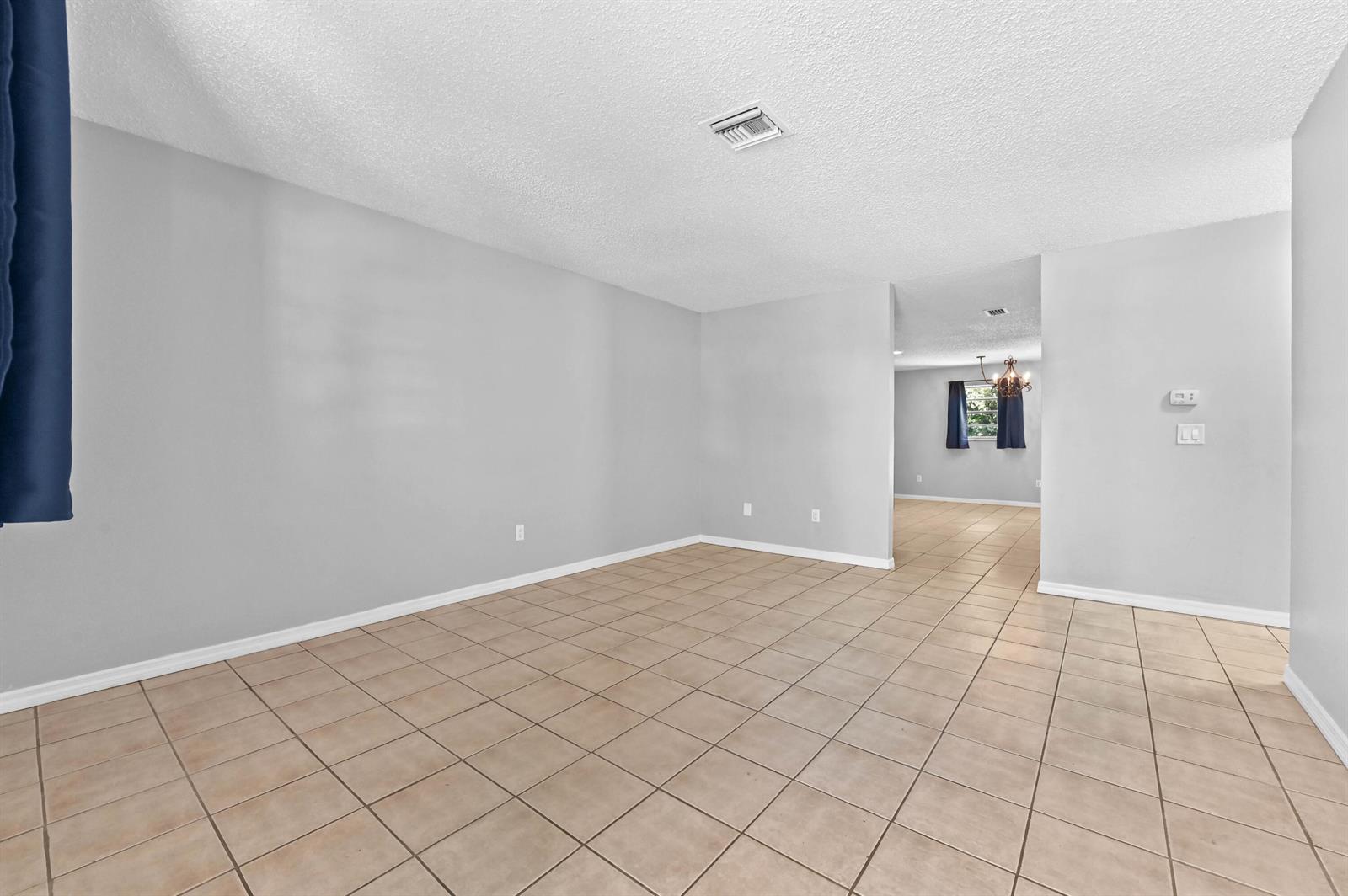 An empty room with light gray walls, white trim, and tan square floor tiles — 4548 SE Salvatori Road, Stuart FL 34997, STUART, FL