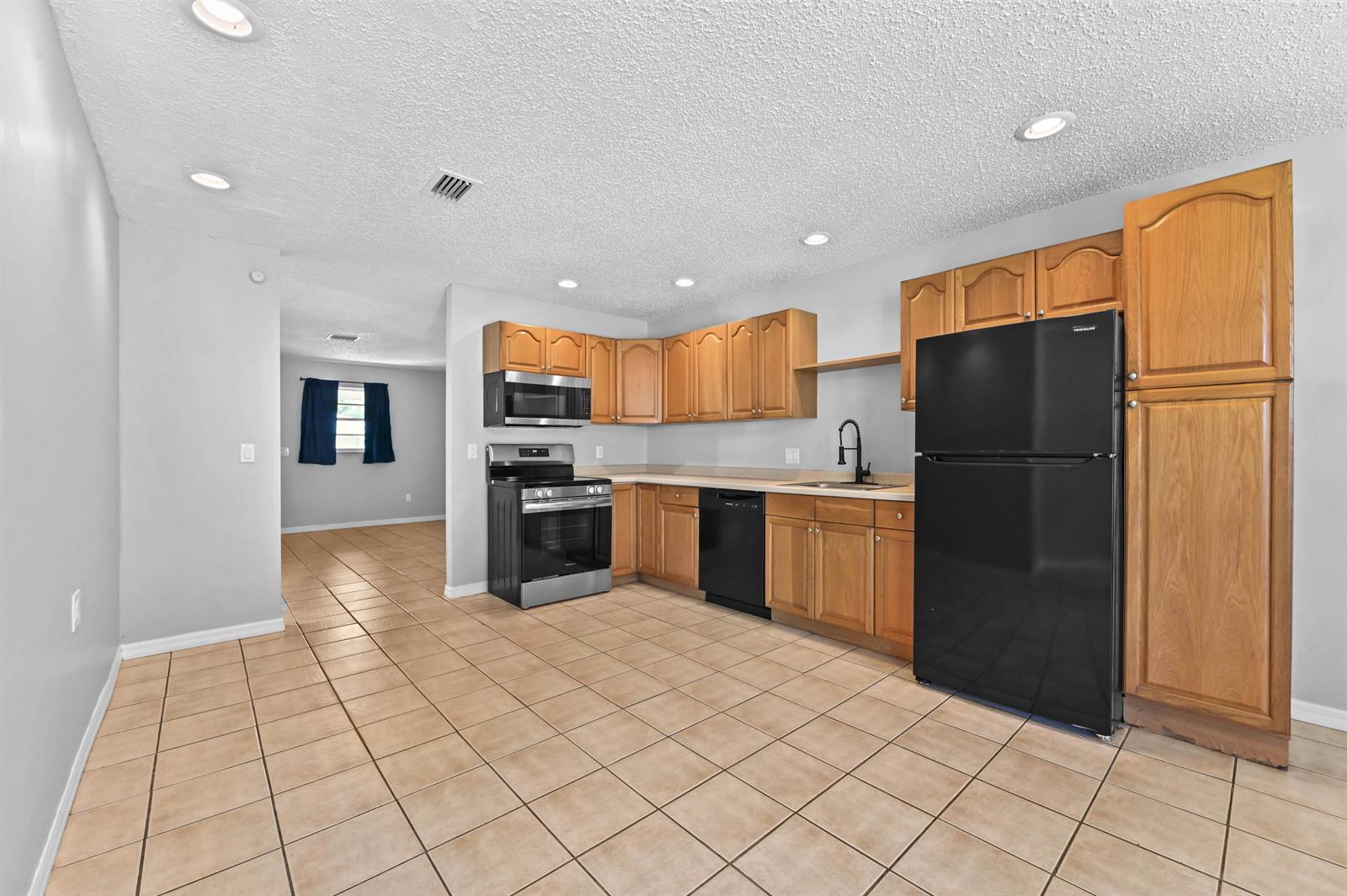 A kitchen features wood cabinets, black appliances, tile flooring, and recessed lighting — 4548 SE Salvatori Road, Stuart FL 34997, STUART, FL