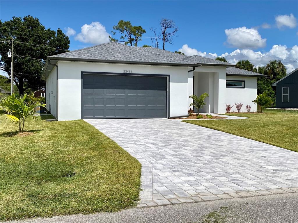 A modern single-story house with a white exterior, gray garage door, and paved driveway — 23466 GARRETT AVENUE, PORT CHARLOTTE, FL