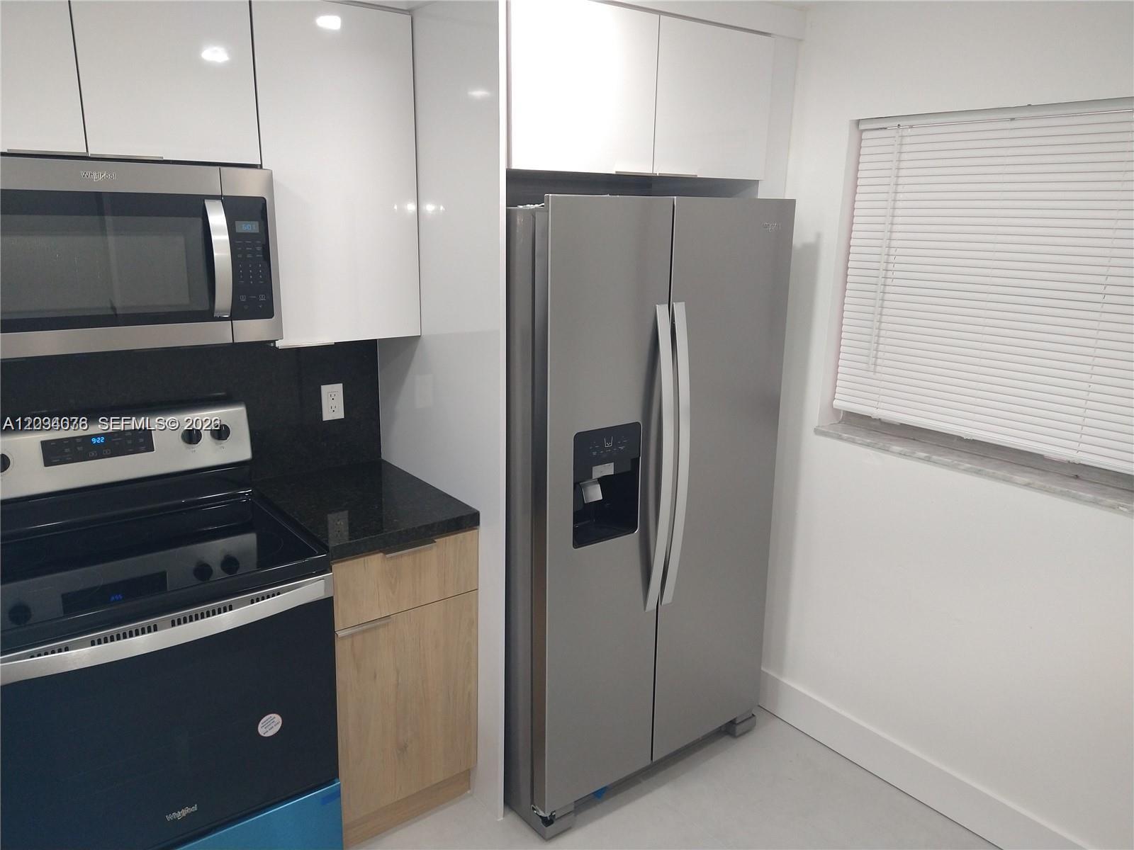 A kitchen features stainless steel appliances, white cabinets, light wood drawers, and black countertops — 19791 SW 114th Ave # 233, Miami FL 33157, MIAMI, FL