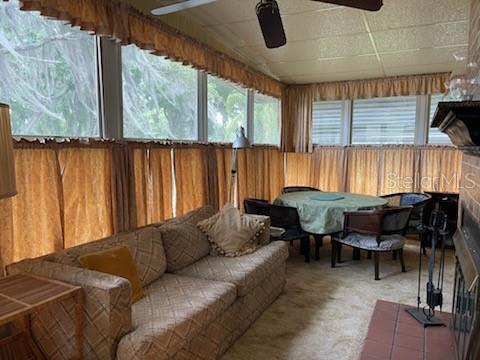 A sunroom features a sofa, a dining table with chairs, and large windows with curtains — 74 N BOBWHITE ROAD, WILDWOOD, FL