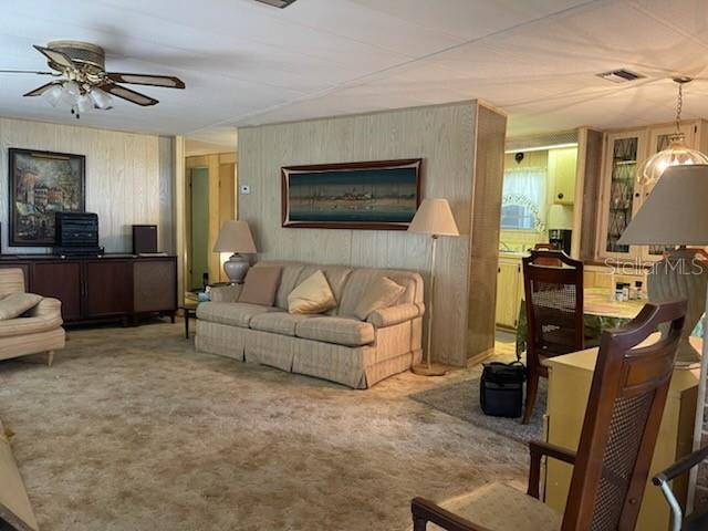 A living room features beige carpet, wood-paneled walls, a tan sofa, and a ceiling fan — 74 N BOBWHITE ROAD, WILDWOOD, FL