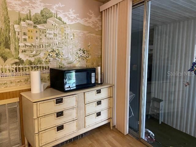A dresser with a microwave sits against a wall with scenic wallpaper near sliding doors — 74 N BOBWHITE ROAD, WILDWOOD, FL
