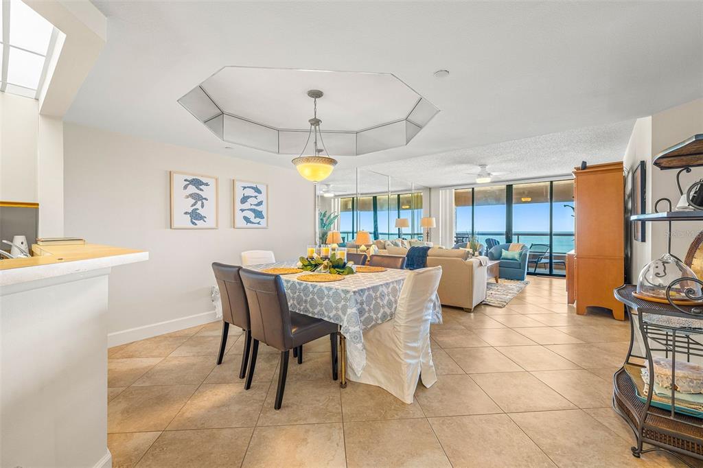 A dining area with a mirrored ceiling feature flows into a living room with ocean views — 1310 GULF BOULEVARD UNIT 10D, CLEARWATER BEACH, FL
