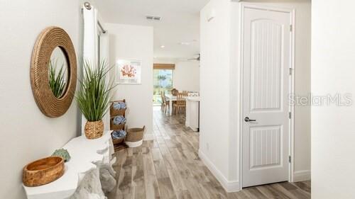 A hallway features a round mirror, a console table, and a door leading to a room — 8123 COCONUT PLACE, KISSIMMEE, FL