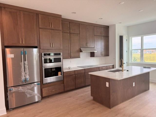 A modern kitchen features brown wood cabinets, stainless steel appliances, and a white island countertop — 9297 LUMINARY BOULEVARD, ORLANDO, FL