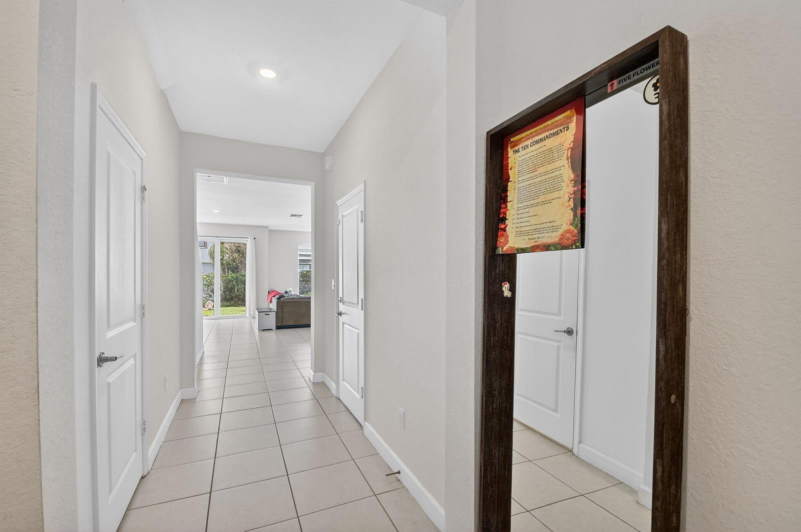 A tiled hallway leads to a living area with a large mirror on the right — 4326 Hammock Grove Drive, Lake Worth FL 33467, LAKE WORTH, FL