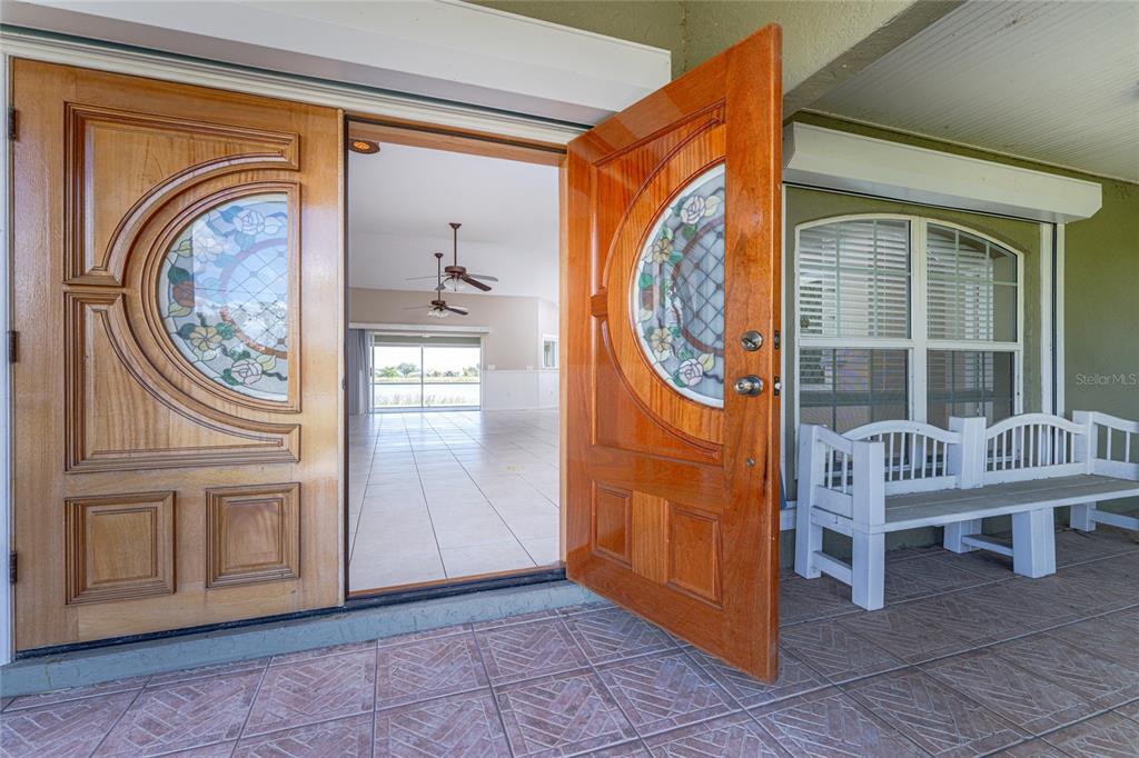A pair of wooden doors with stained glass inserts open to a tiled interior room — 7110 SAN CASA DRIVE, ENGLEWOOD, FL