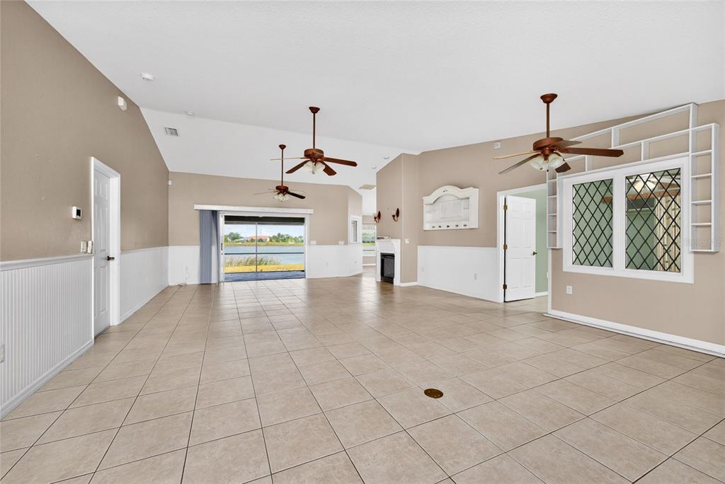 A spacious living room features tile flooring, vaulted ceilings, two ceiling fans, and a fireplace — 7110 SAN CASA DRIVE, ENGLEWOOD, FL