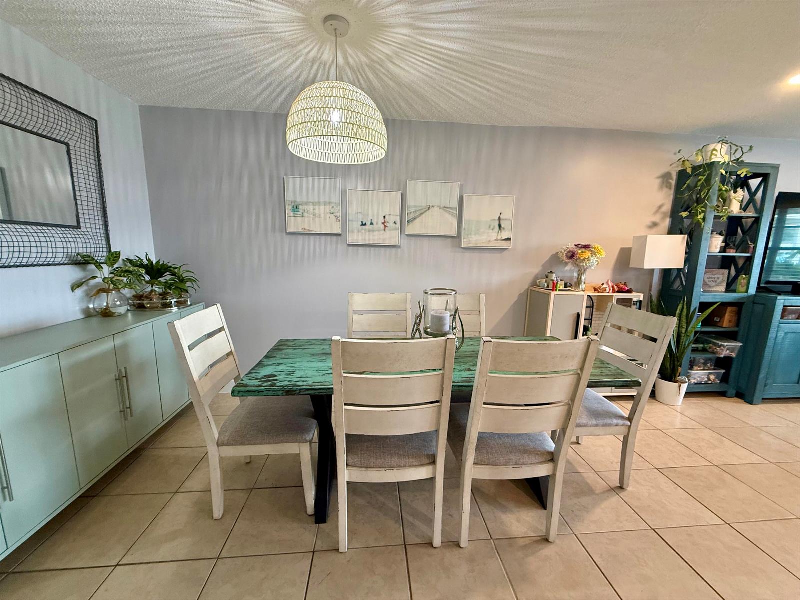 A dining room features a distressed green table, white chairs, and a woven pendant light — 4441-4443 SE Village Road, Stuart FL 34997, STUART, FL