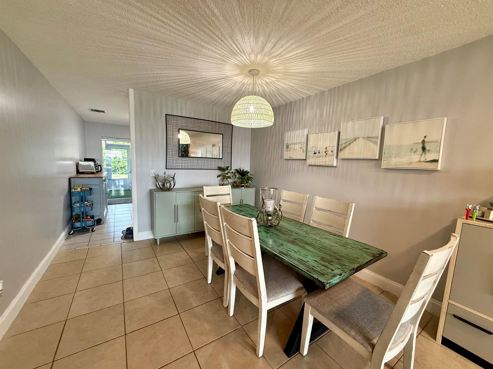 A dining room features a distressed green table, white chairs, and a textured ceiling light — 4441-4443 SE Village Road, Stuart FL 34997, STUART, FL