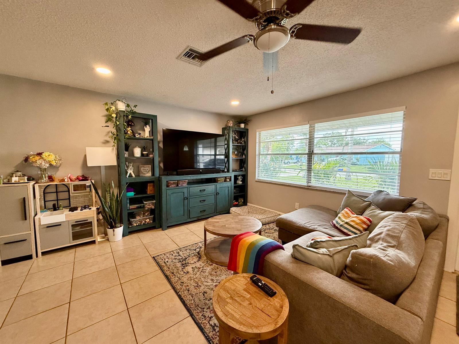 A living room features a sectional sofa, a teal media console, and a play kitchen — 4441-4443 SE Village Road, Stuart FL 34997, STUART, FL