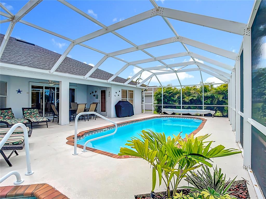 A screened-in patio features a swimming pool, outdoor seating, and a grill — 119 SPORTSMAN ROAD, ROTONDA WEST, FL