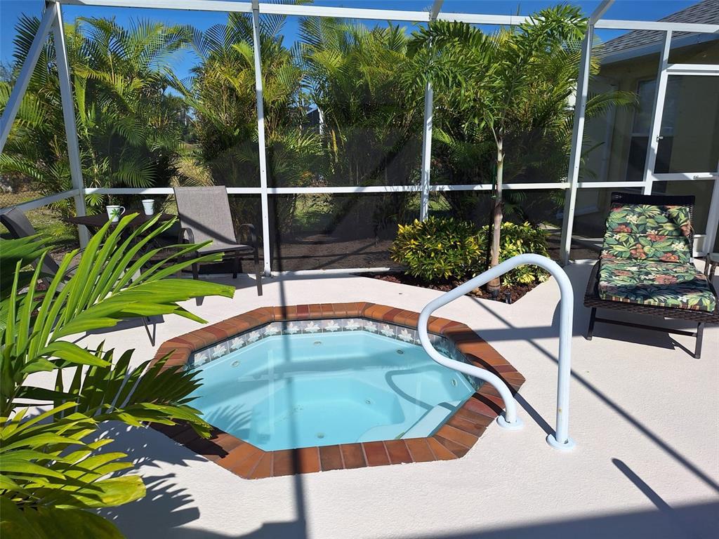 An outdoor screened-in patio features a built-in hot tub with brick coping and lounge chairs — 119 SPORTSMAN ROAD, ROTONDA WEST, FL