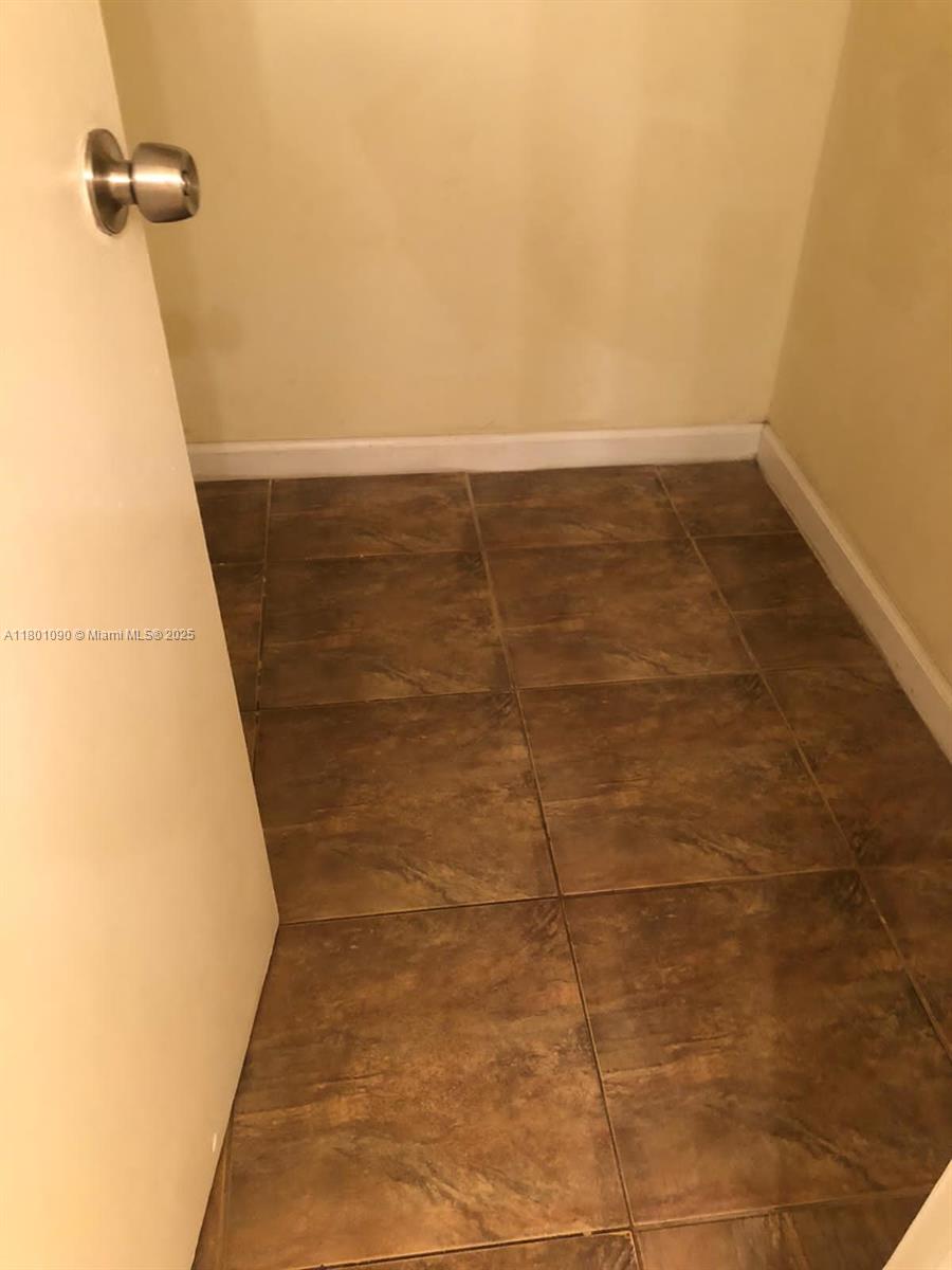 This small closet features brown tiled flooring and beige walls — 492 NW 165th St Rd # C514, Miami FL 33169, MIAMI, FL