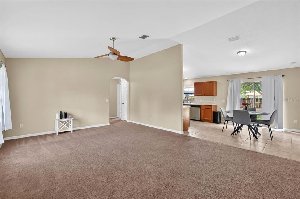 A carpeted living room opens into a tiled dining area and kitchen with wooden cabinets — 1520 3RD AVENUE, DELAND, FL