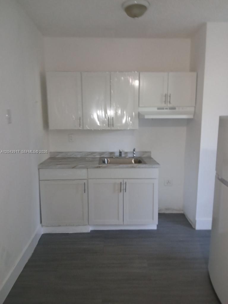 A small kitchen features white cabinets, a stainless steel sink, and grey wood-look flooring — 1003 SW 15th Ave # 6, Miami FL 33135, MIAMI, FL