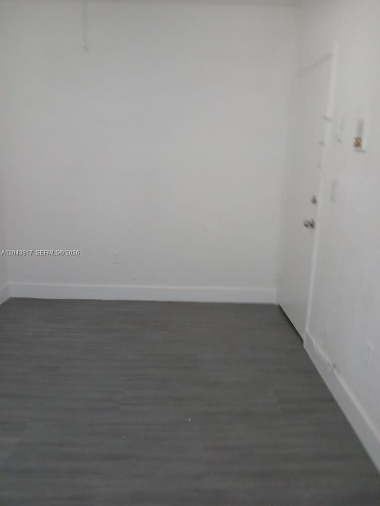 An empty room features white walls, gray wood-look flooring, and a white door — 1003 SW 15th Ave # 6, Miami FL 33135, MIAMI, FL