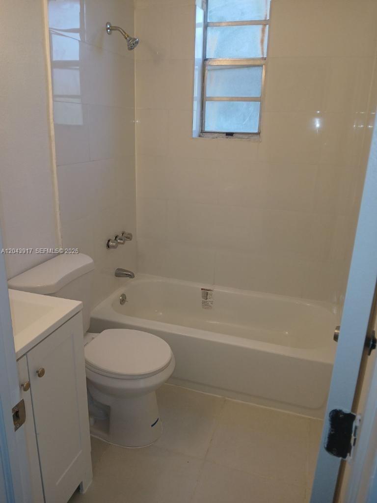 A small bathroom features a white vanity, toilet, and a bathtub with a shower head — 1003 SW 15th Ave # 6, Miami FL 33135, MIAMI, FL